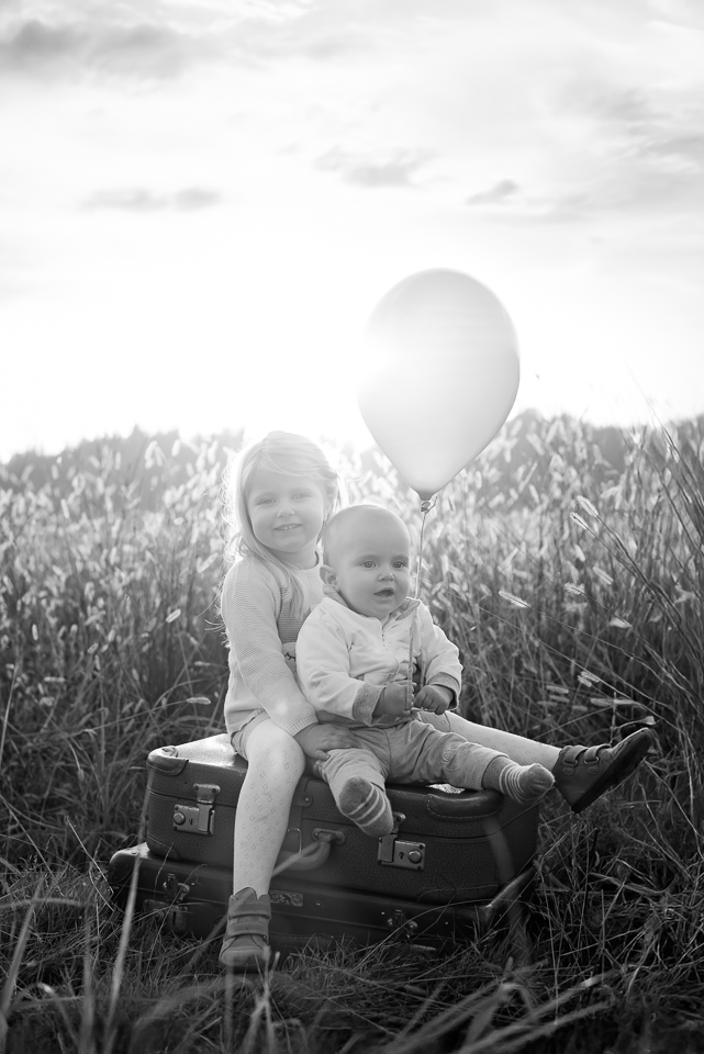 Geschwisterfoto auf Koffer mit Ballon